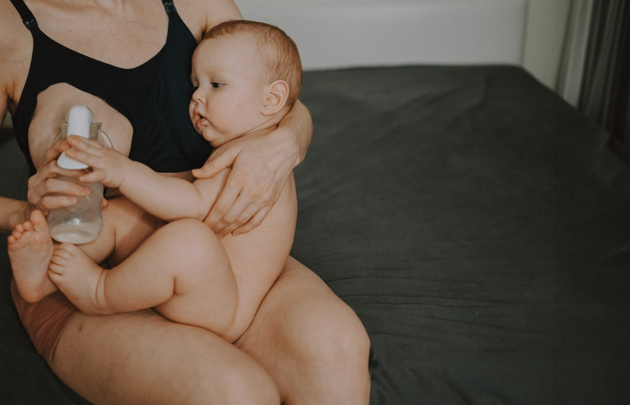 Mom holding baby while breast milk pumping