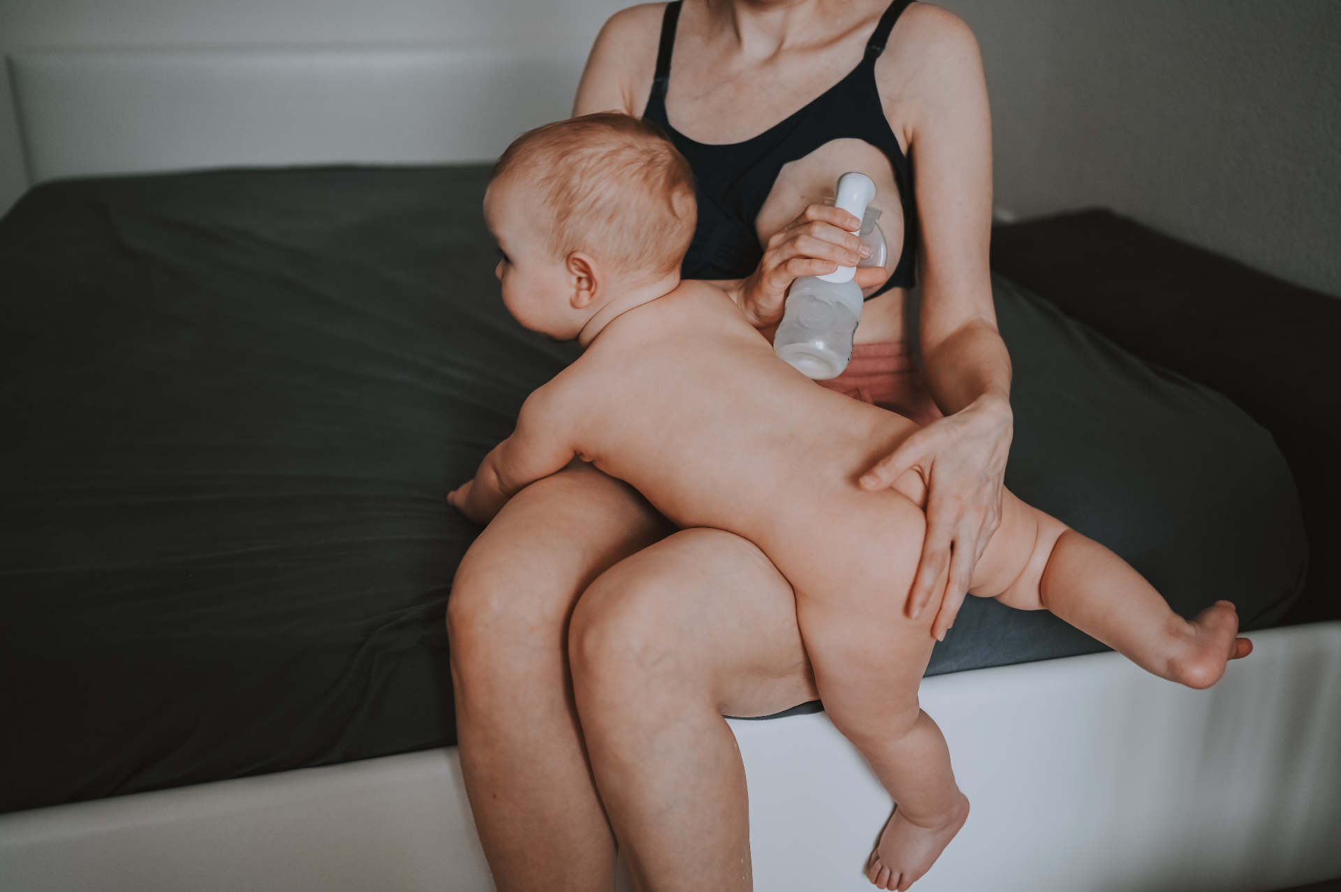 Mother holding her baby while using a breast pump