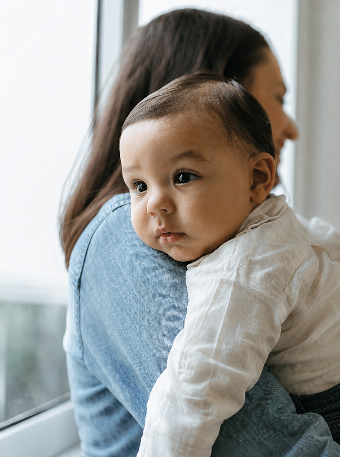 Parent holding a baby by a window