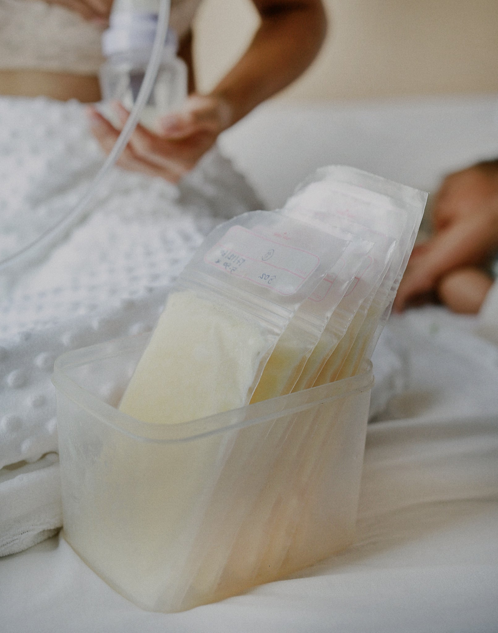 Mom pumping behind container of frozen breast milk