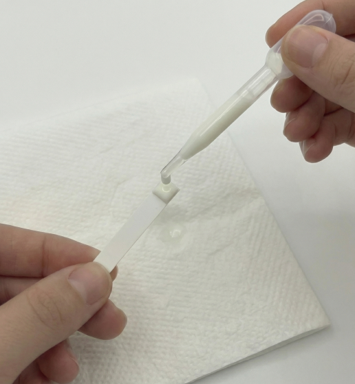 Pipette dispensing breast milk onto a test strip